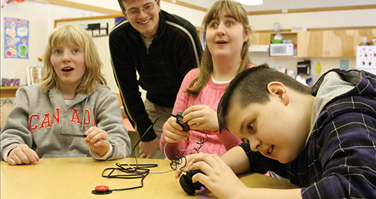 A CanAssist client and other students at Lansdowne Middle School examine the CanAssist iPod adapter system.