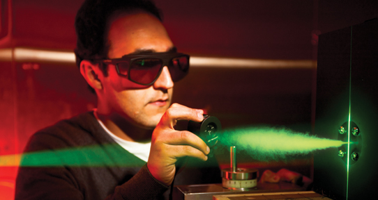 UVic male researcher in a lab working with green laser light fuel cell