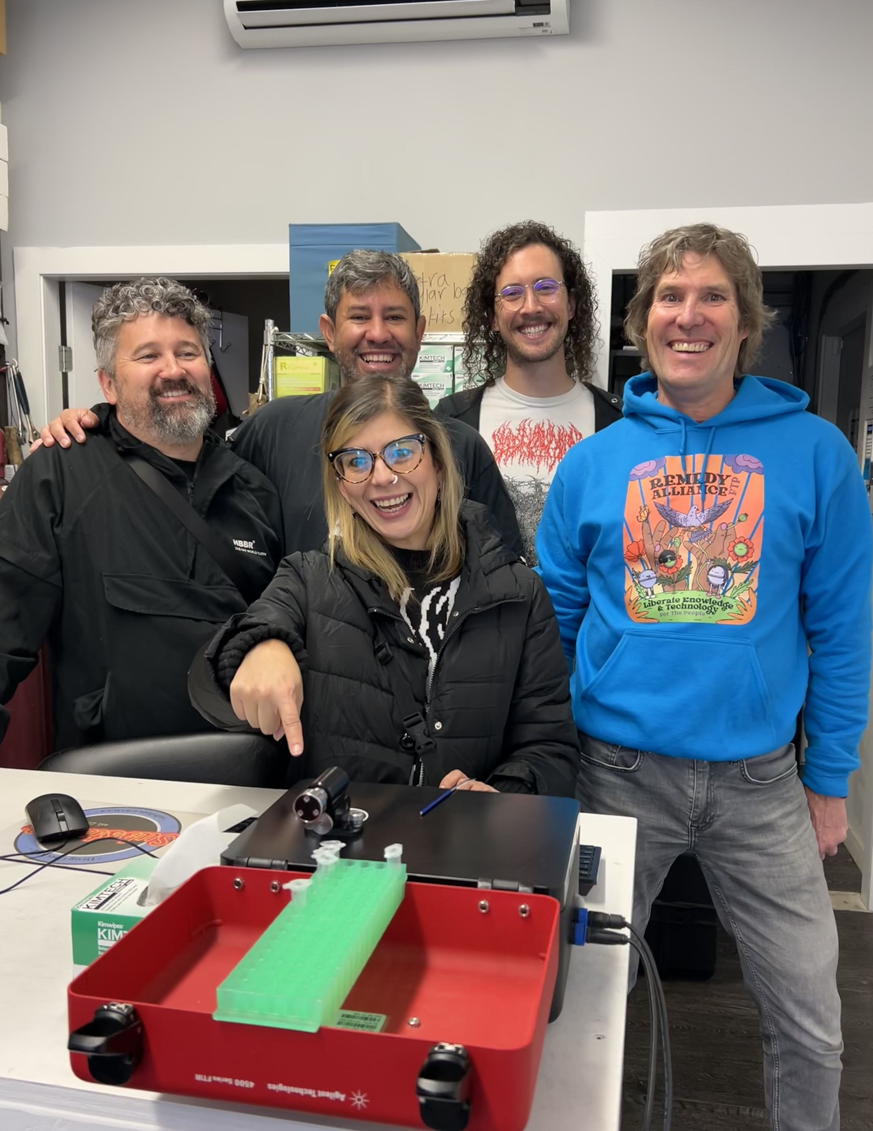 A photo of Julian Quintero (left), Jaime Arredondo, Colin Kielty, Bruce Wallace and Vanessa Morris (front centre) posing in front of a drug checking machine