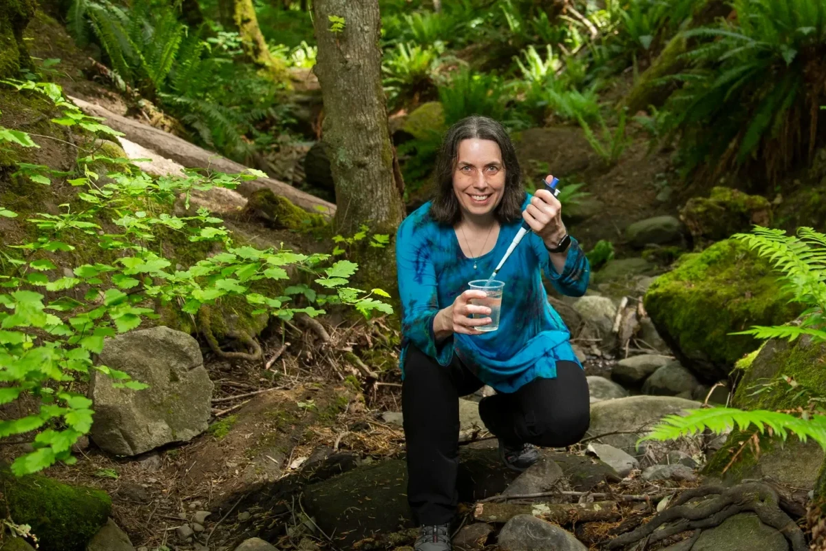 Caren Helbing crouched in the forest collecting samples