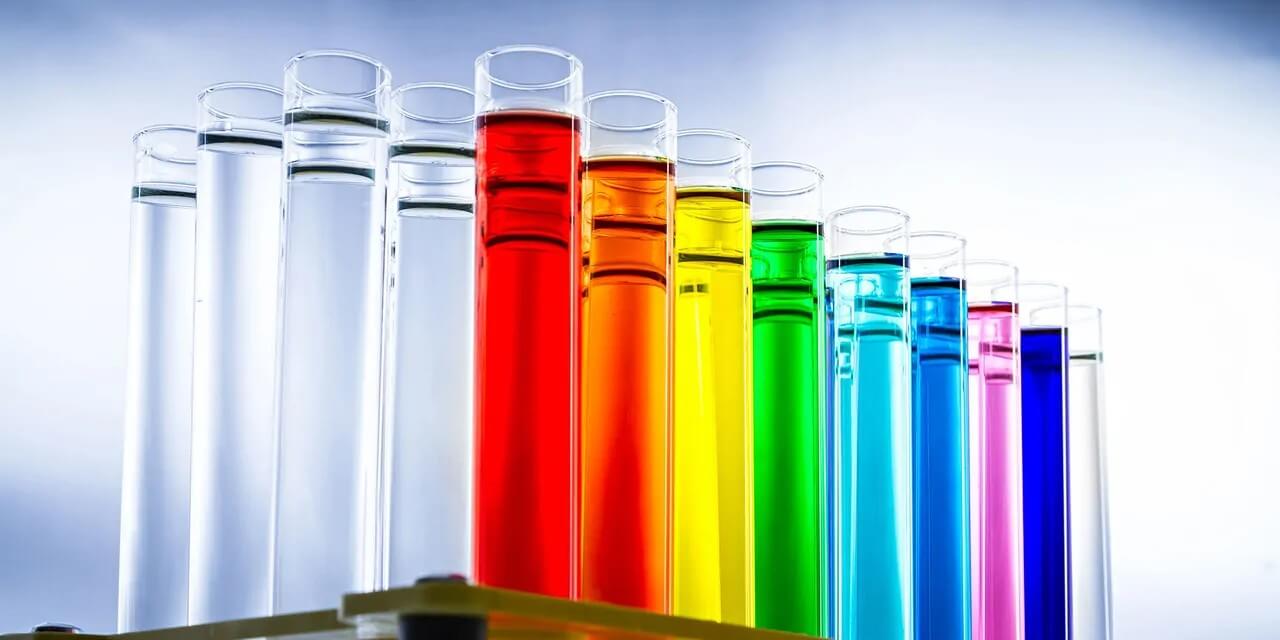 Test tubes filled with liquid in the colours of the Pride flag