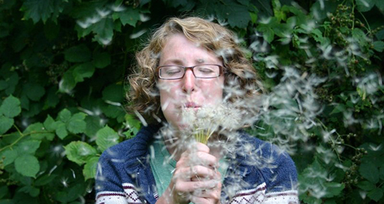 Female co-op student blowing milkweed seeds