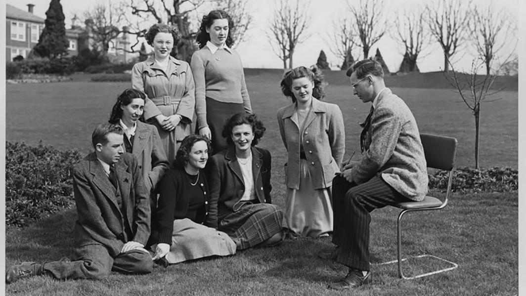 Black and white photo of students and teacher outside on a lawn