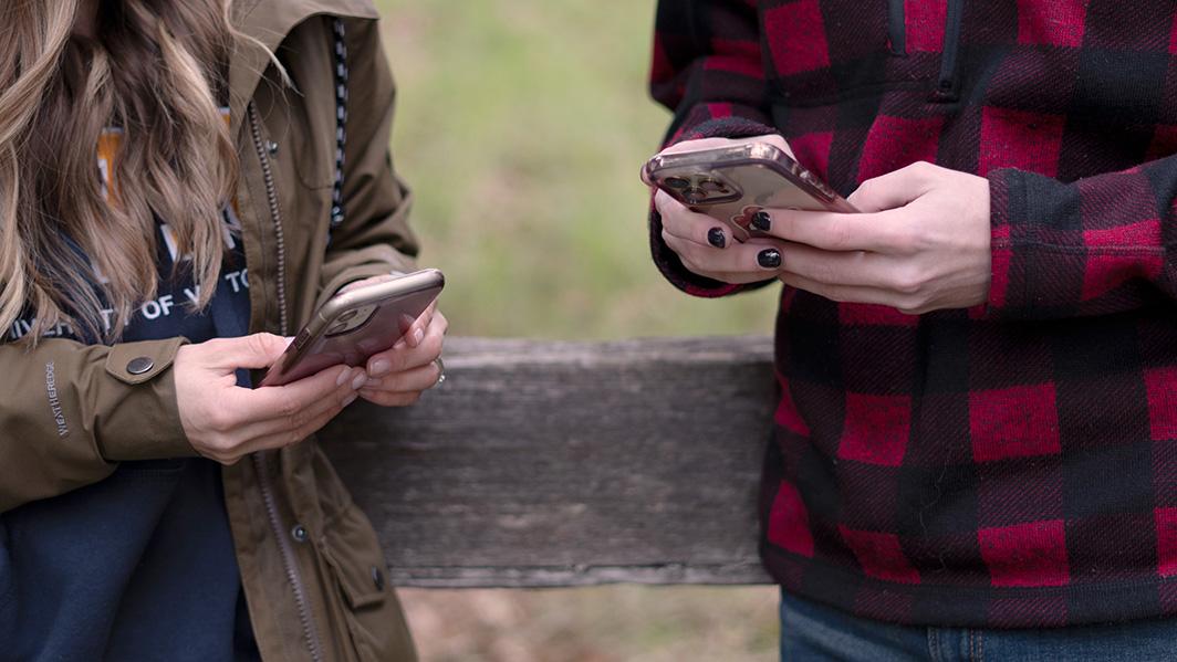 Two students searching for information on their phones