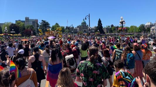 A large group of people gather outside in Victoria's inner harbour.
