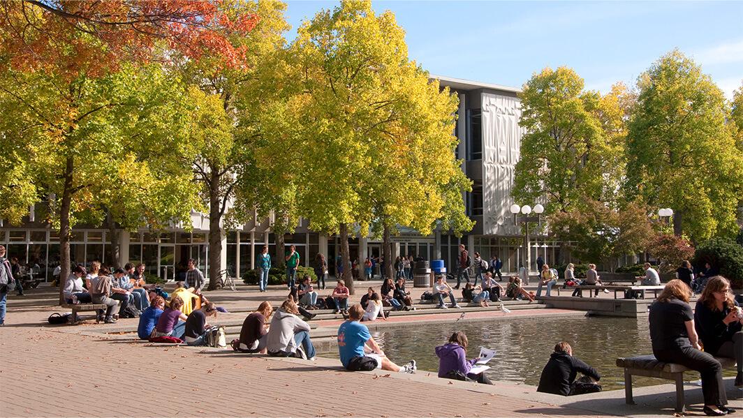 Students congregate outdoors in the quad in front of the library.