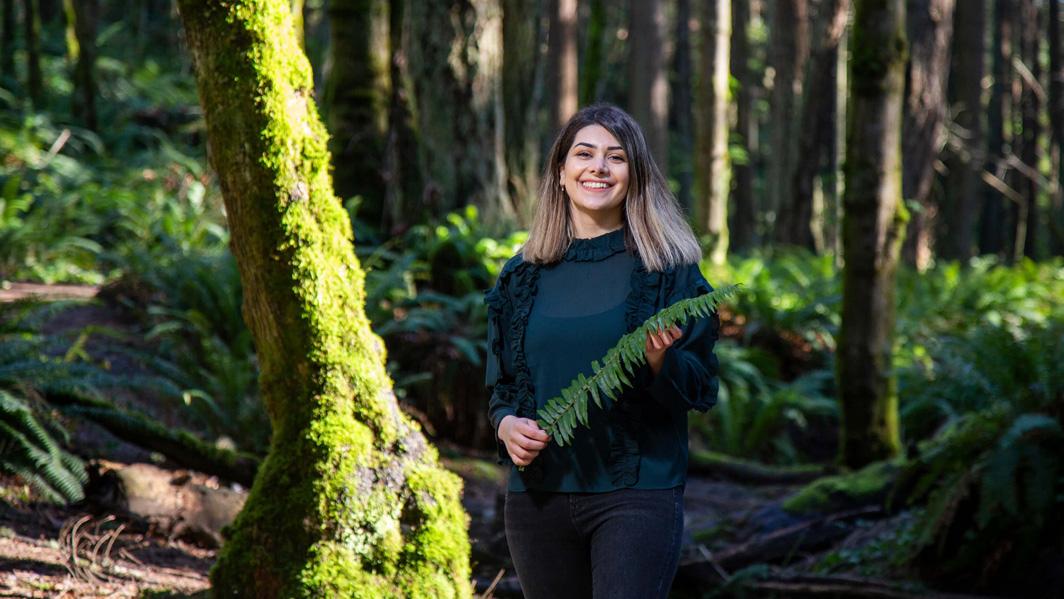 student holding fern in forest setting