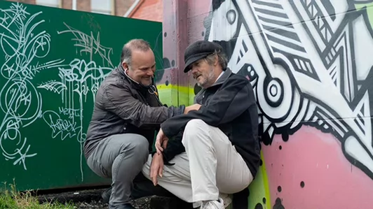 A man using a stethoscope on a patient in the street 