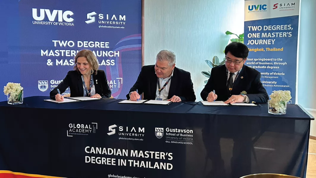 Image of three individuals signing an institutional agreement at SIAM University