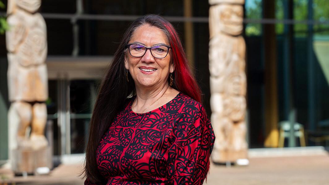 Qwul’sih’yah’maht Robina Thomas stands in front of First Peoples House at UVic.