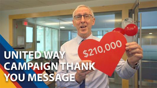 Photo of UVic President Kevin Hall smiling at the camera while holding a heart shaped sign with the number: $210,000 and the the legend: "United Way Campaign Thank you message"
