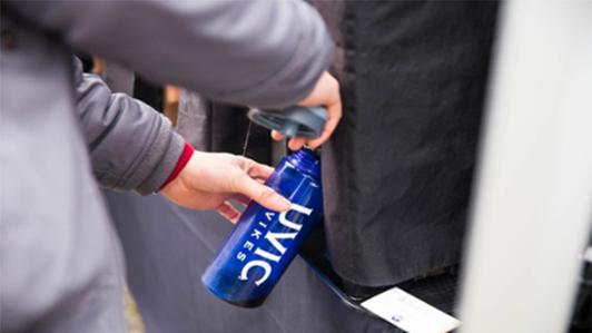 Stock picture of a "UVic Vikes" branded aluminum bottle being refilled at a drinking water fountain  on campus