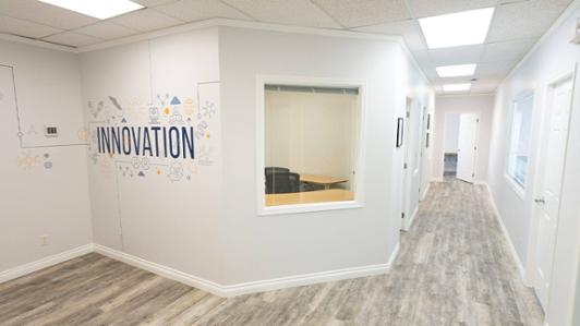 Photo of the hall of brand new UVic's Innovation Hub showing a decorated wall with symbols allusive to creativity, with the text: "INNOVATION"