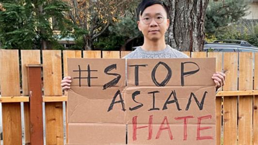Photo of Dr. Nigel Mantou Lou holding a cardboard sign with the text: "# STOP ASIAN HATE"