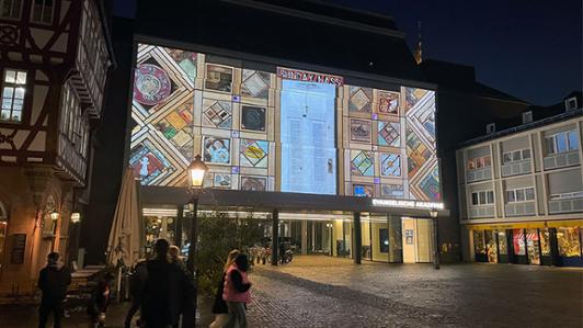 Photo by night of Carey Newman’s Witness Blanket projected onto a building façade in Frankfurt’s Romberg Plaza in October 2021 