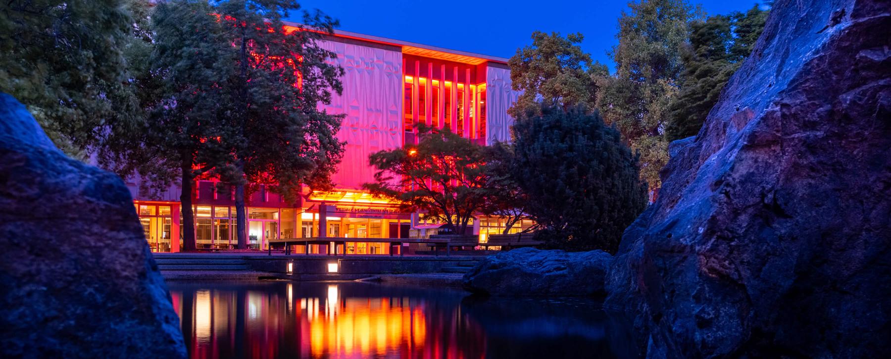 UVic library lit up in orange lights at dusk, in honour of the remains of 215 children found at the former Kamloops Residential School.