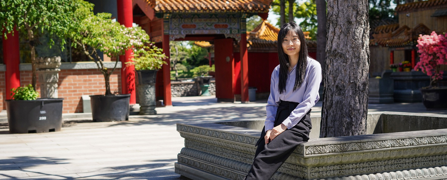 A woman in a purple shirt sits in a courtyard
