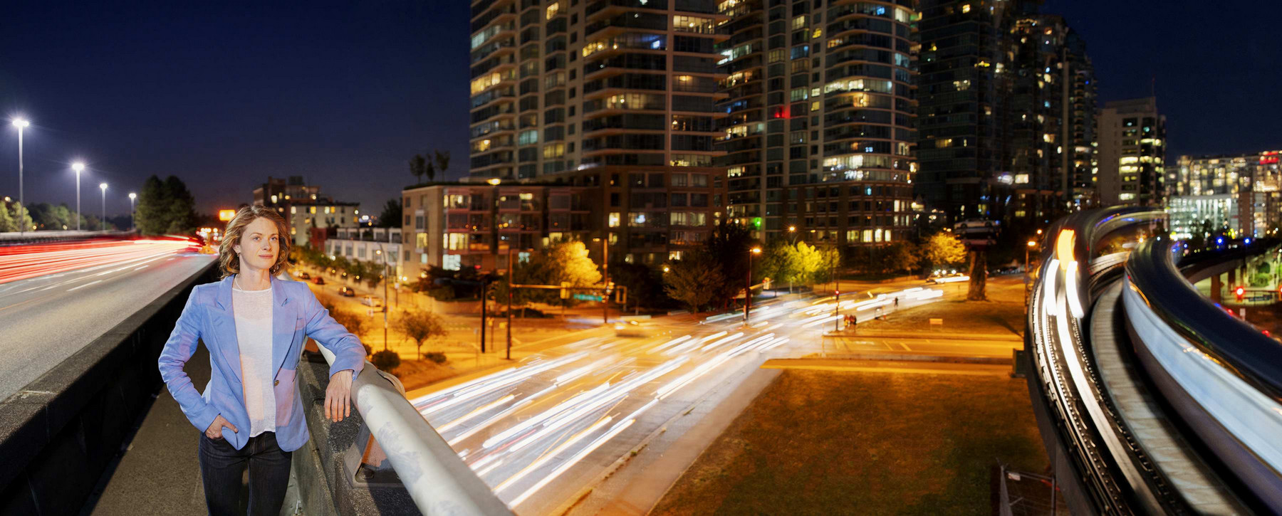 McPherson standing on a Vancouver city bridge at night with roads and buildings in background.