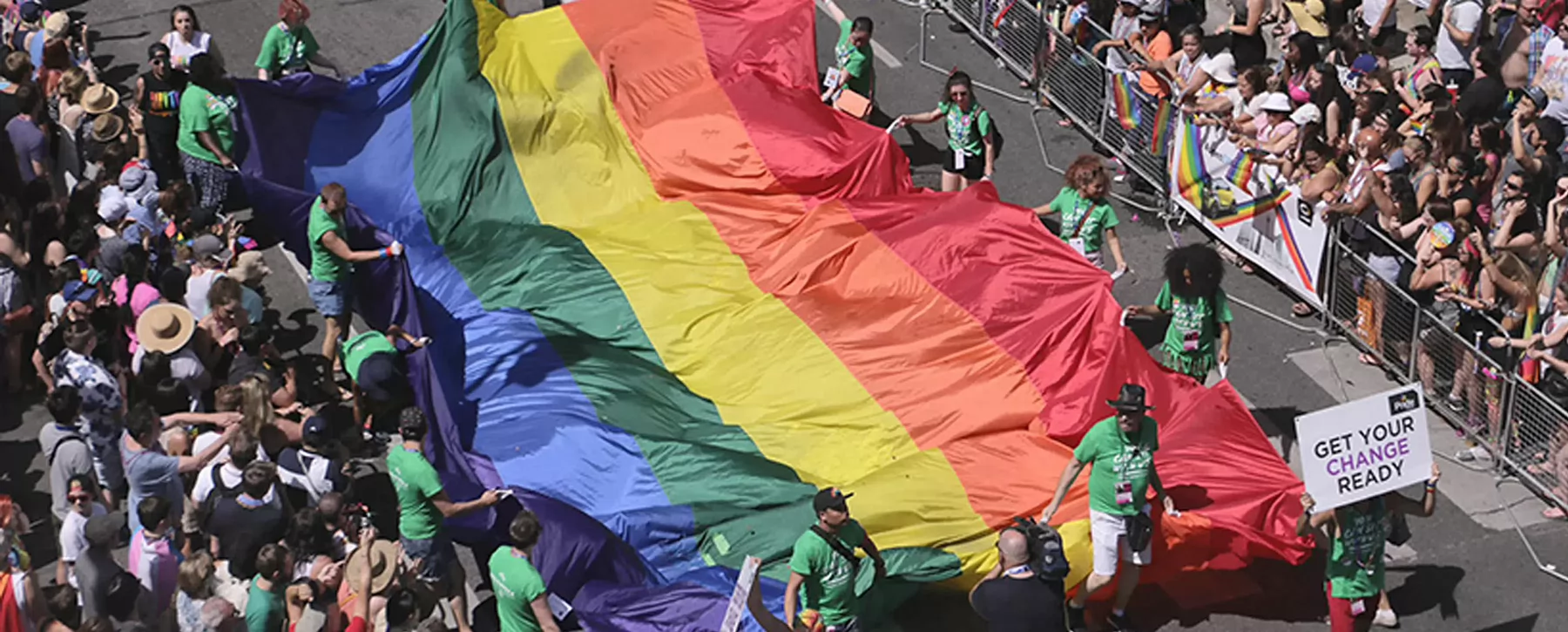 People holding up a rainbow flag at a Pride parade.