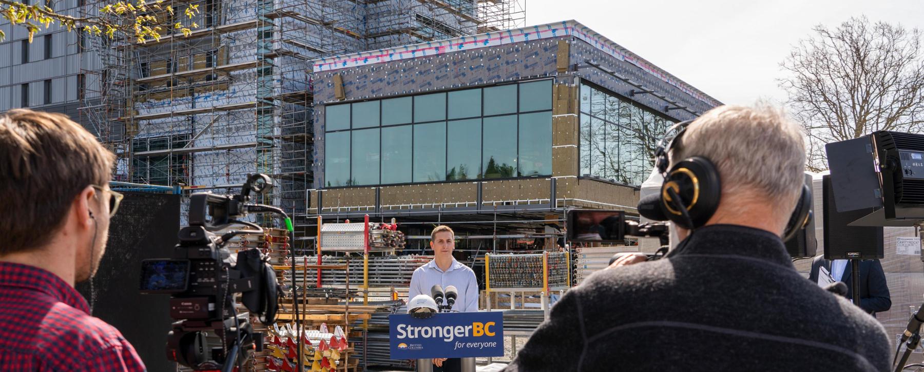 man at podium in front of construction