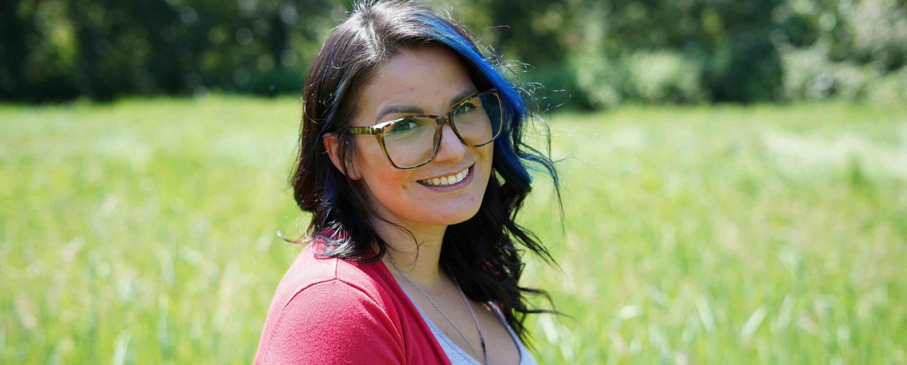 Shirina Evans smiling at the camera standing in front of a green field 