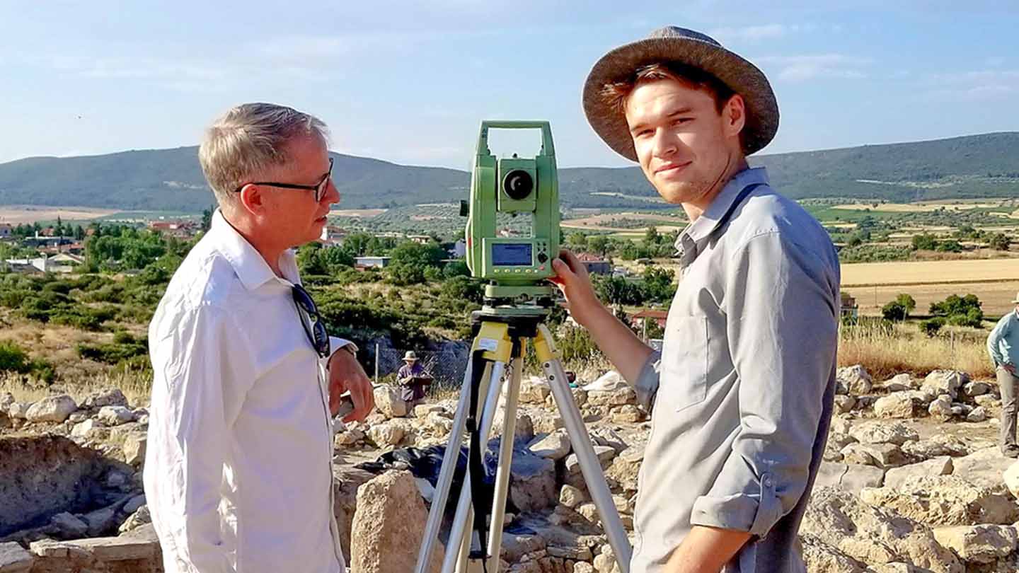 Burke (left) conducts a field survey of the ancient site of Eleon with co-op student Graham Braun.