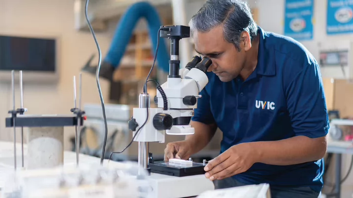 Photo of a UVic engineer looking at a microscope in a Lab at UVic