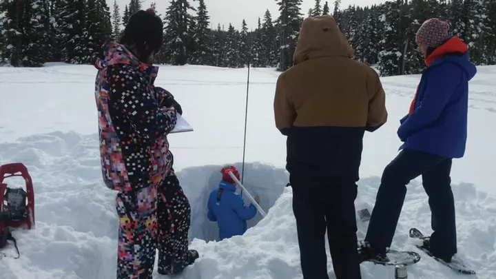 Photo of UVic students digging a hole in the snow as part of a field school 