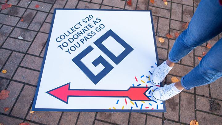 Close up of a person standing on a board-game style GO floor sign.