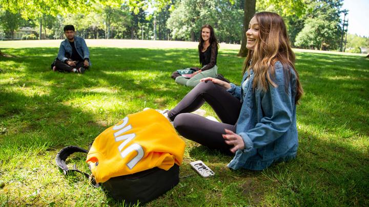 A group of students sit socially-distanced on the lawn in the UVic quad.