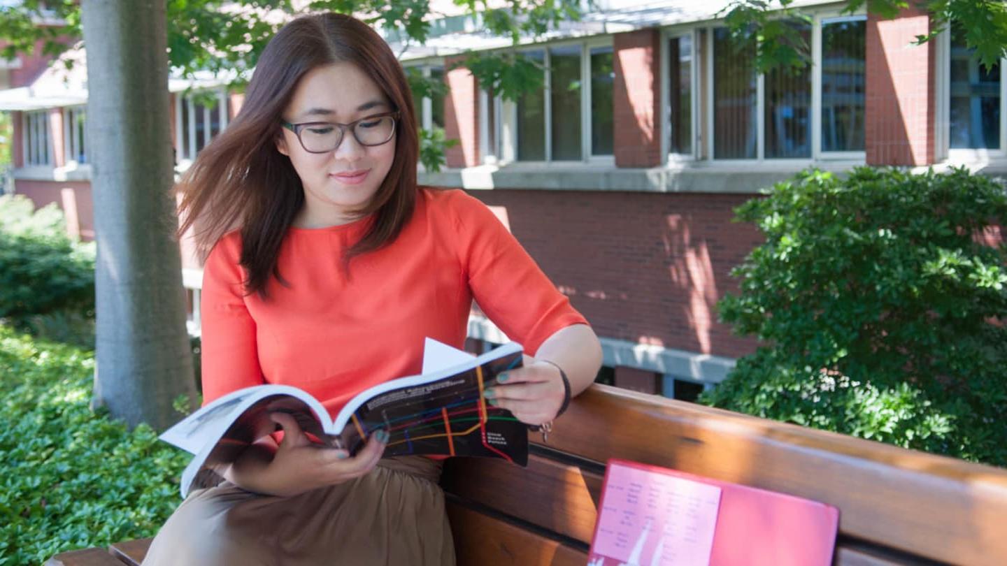 student on bench reading book