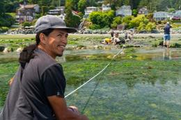 An Indigenous man turns to the camera and smiles during a field school trip to Cordova Bay.