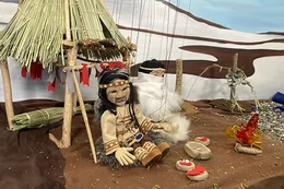 Two puppets, Elvel and her father are posed in front of a fire prop during filmmaking.