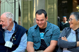 Three people sit together in a line, each smiling.