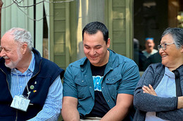 Three people sit together in a line, each smiling.