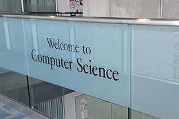 The Computer Science welcome sign on the glass railing in the ECS building.