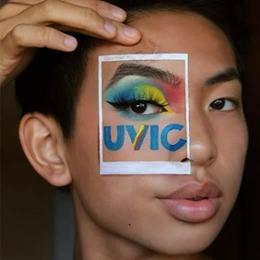 Student posing with makeup around eye that spells "UVic".