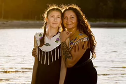 Dani and her mom, Danita embracing in front of a water landscape.