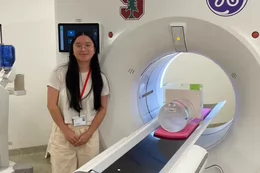 A student stands next to a CT scan machine.