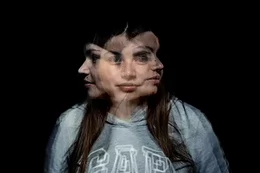 A creative interpretation of a deep fake image by AI: a woman facing the camera has copies of her head facing left and right super-imposed upon the portrait.