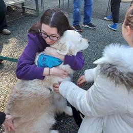 Student hugs a fluffy dog at the pet cafe.