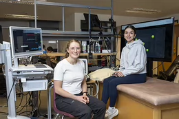 Emma Skaug and Ella Lane sit in a lab.