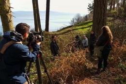 Students capturing photos in the forest, ocean in the background.