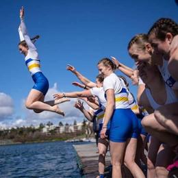 Women's Vikes Rowing team throwing their coxswain into the water from the dock after winning.