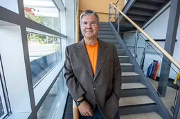 Tim Naimi stands on stairs beside a window.