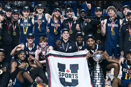 The UVic men’s basketball team celebrate the program’s ninth national title by posing with the U SPORTS banner and W.P. McGee Trophy.