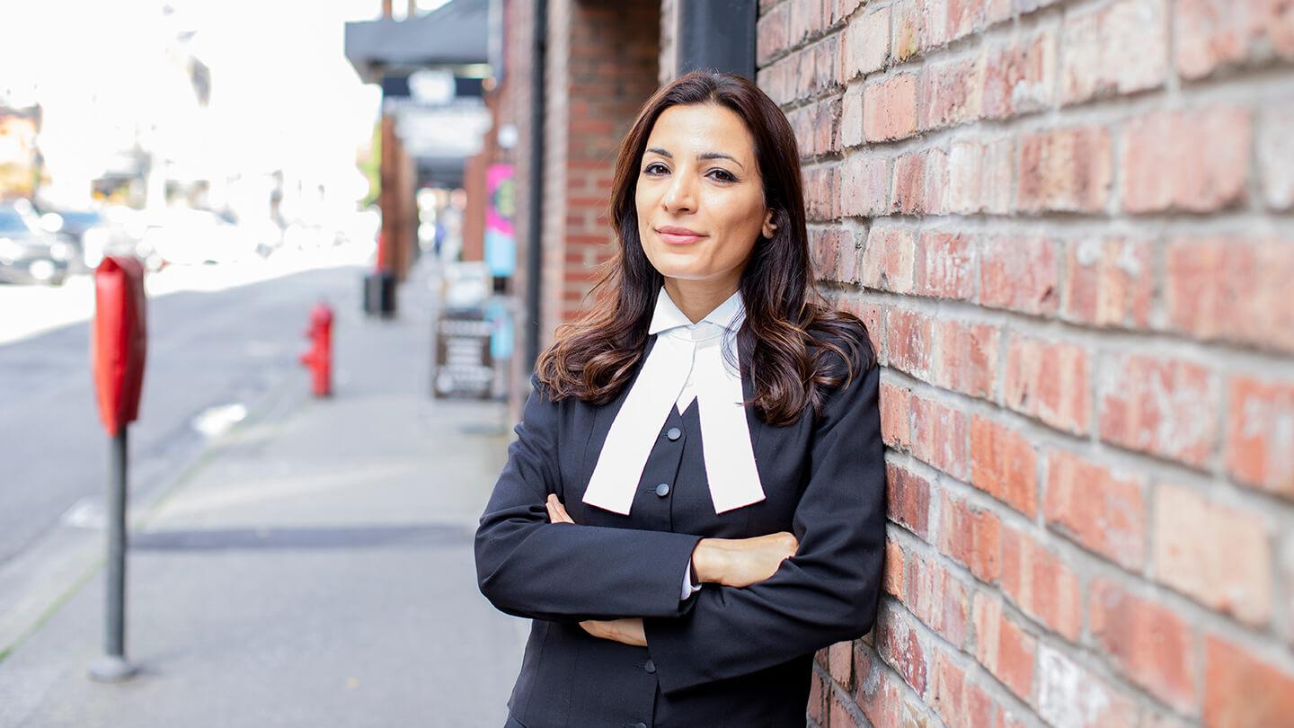 Lawyer Leena Yousefi leaning against a brick wall.