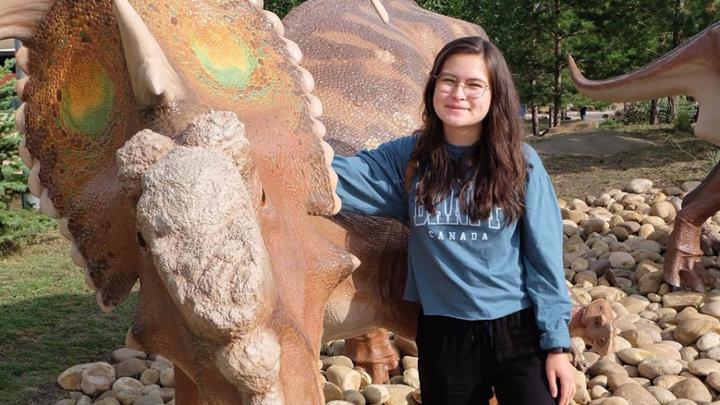 student in front of dinosaur replica