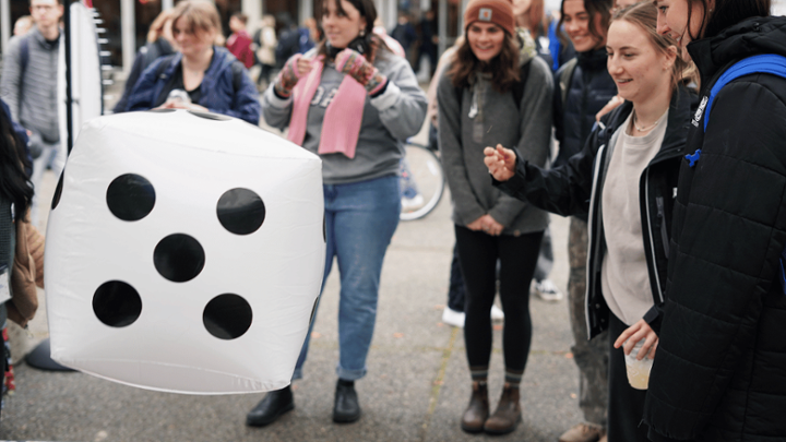 student smiling rolling a giant dice