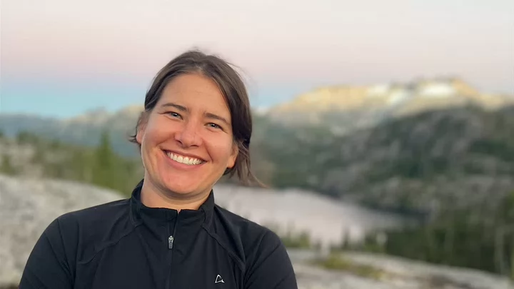 Jessica smiling with sunset-tinged mountain vista in background